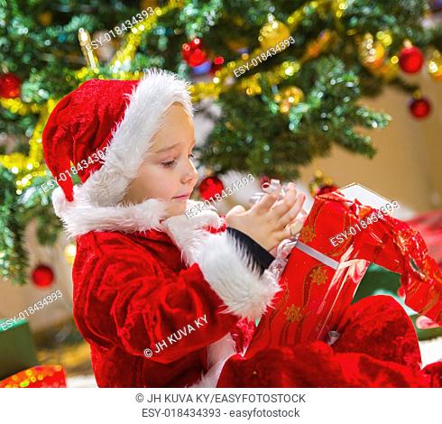 Boy opens a Christmas gift, Christmas tree and gifts on background