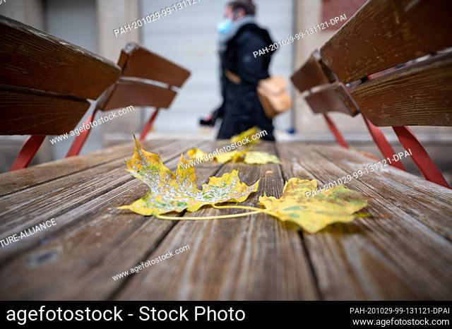 29 October 2020, Baden-Wuerttemberg, Stuttgart: Passers-by walk past a closed bar that does not open until the afternoon