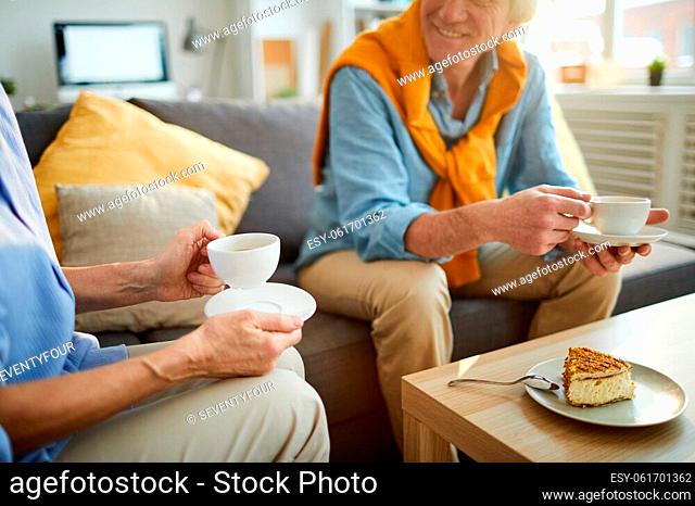 Mid section portrait of unrecognizable mature couple enjoying tea during weekend at home, copy space