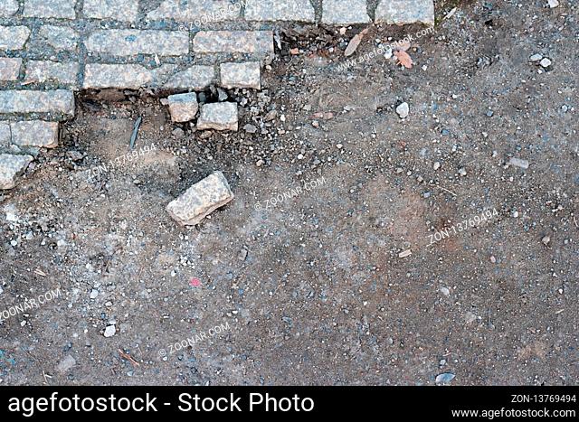 A damaged footpath with a single cobblestone