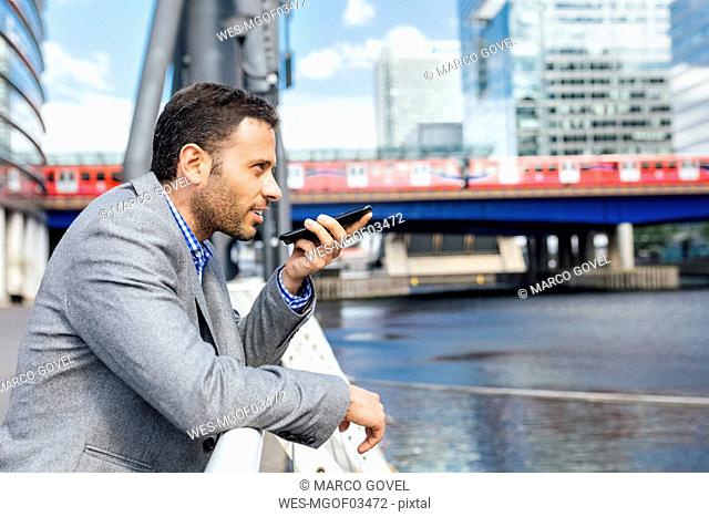 Businessman sending voice messages with his smartphone in the city