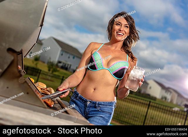 A beautiful brunette model enjoying a day outside while cooking on a grille
