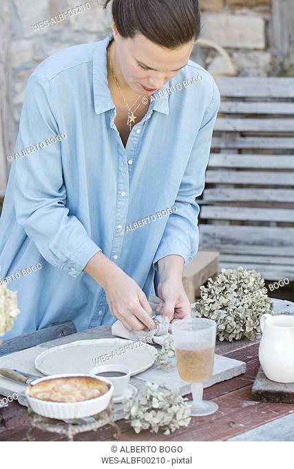 Italy, woman laying breakfast table on terrace