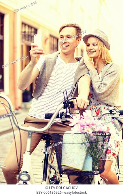 summer holidays, love, navigation, gps and dating concept - smiling couple with bicycles and smartphone in the city