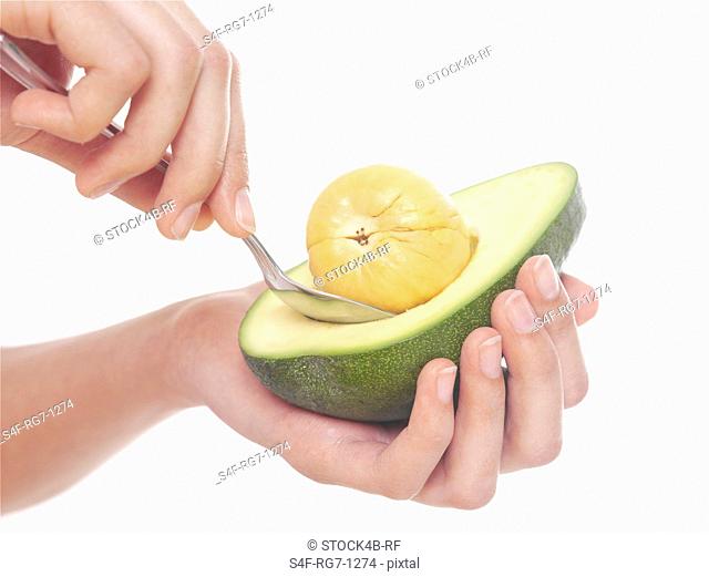 Hand holding avocado and spoon