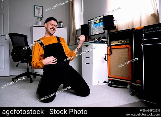 Man playing air guitar kneeling in home studio