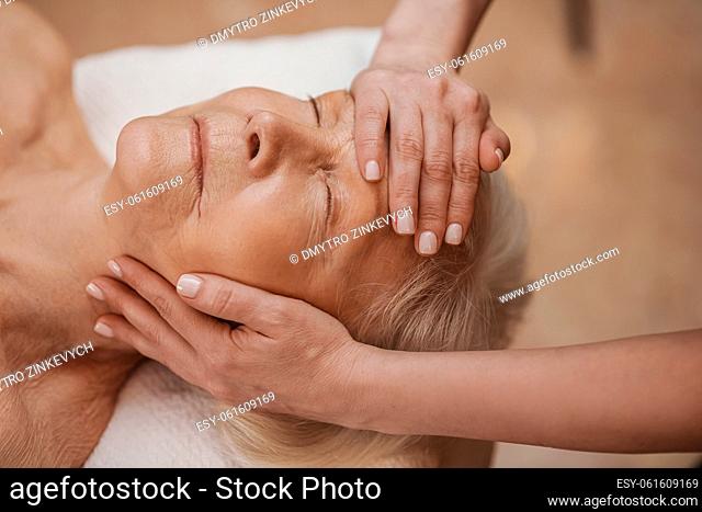 Face massage. A senior woman having a face massage in a beauty salon