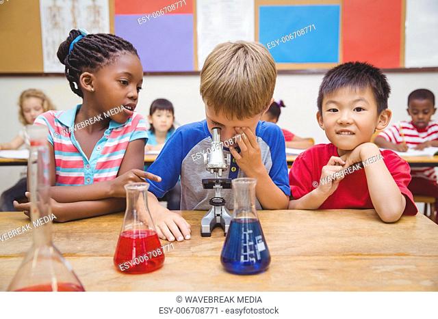 Cute pupil looking through microscope