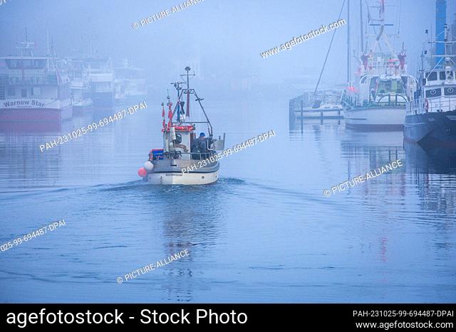 25 October 2023, Mecklenburg-Western Pomerania, Rostock: A fisherman sails his cutter in the direction of the Baltic Sea in dense fog on the Alter Strom in...