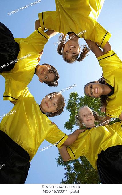 Five children soccer players 7-9 years huddling view from below portrait