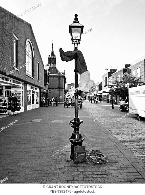 Street Entertainer Playing a Flute Whilst Hanging From a Lamp Post, Lewes, Sussex, England