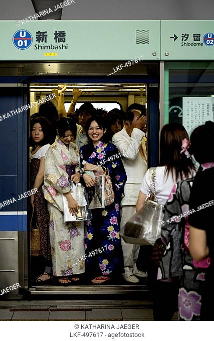 Crowded subway train with two laughing modern geisha girls at Shinbashi Station, Tokyo, Kanto Region, Honshu, Japan