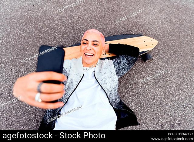 Skateboarder lying on board and using phone