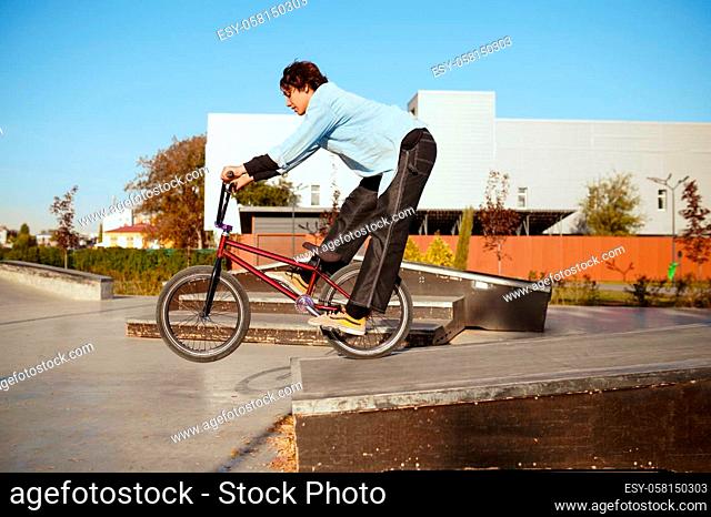 Young bmx biker doing trick, training in skatepark. Extreme bicycle sport, dangerous cycle exercise, risk street riding, biking in summer park