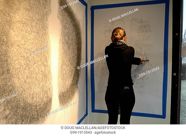 A woman artist works on a ""performance painting"" in the bay window of her studio. The public work featured obsessive, repetitive moment and took over two...
