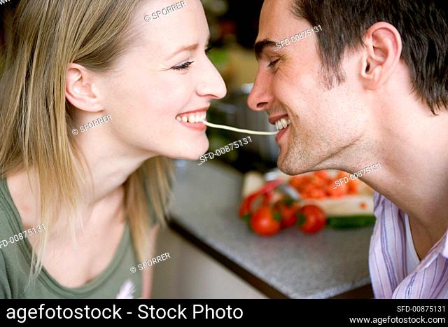 Young couple eating the same strand of spaghetti