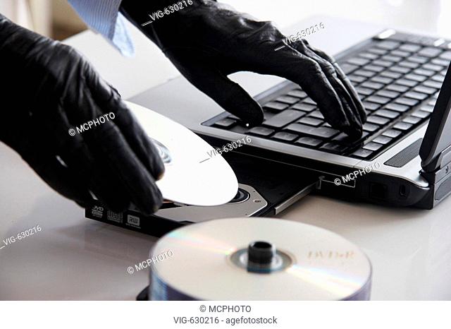 Haende in Handschuhen, ein Laptop und einige discs, gloved hands, a laptop and some discs - GERMANY, 08/02/2008