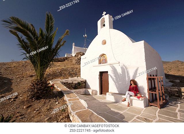 Woman sitting in front of a chapel at the top of the hill in Chora, Ios, Cyclades Islands, Greek Islands, Greece, Europe