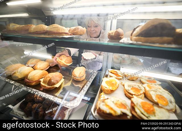 20 September 2021, Hamburg: Angelika Freitag takes a roll from the refrigerated counter at Odo's Kaffeeklappe in Steinwerder harbor