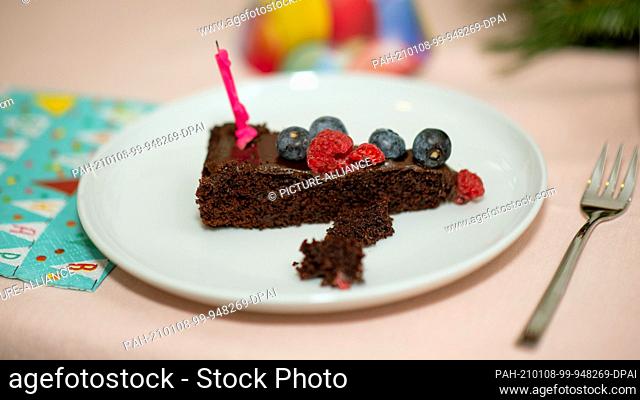 12 December 2020, Saxony-Anhalt, Magdeburg: On a plate is a piece of chocolate cake with raspberries, blueberries and a candle