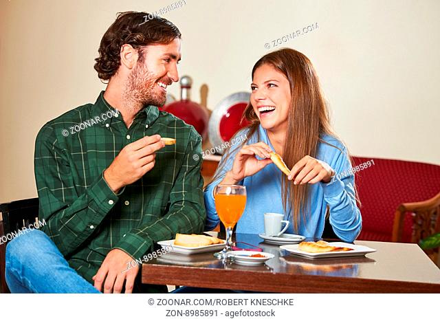 Glückliches Paar macht Urlaub im Hotel und sitzt beim Frühstück zusammen