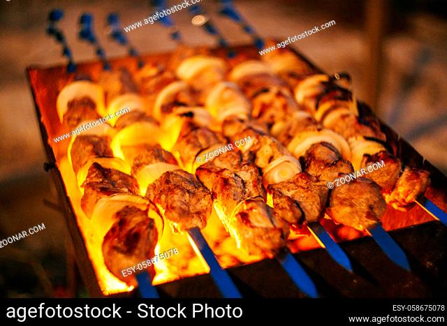 pieces of meat are friend on fire on skewers on grill. close up. High quality photo