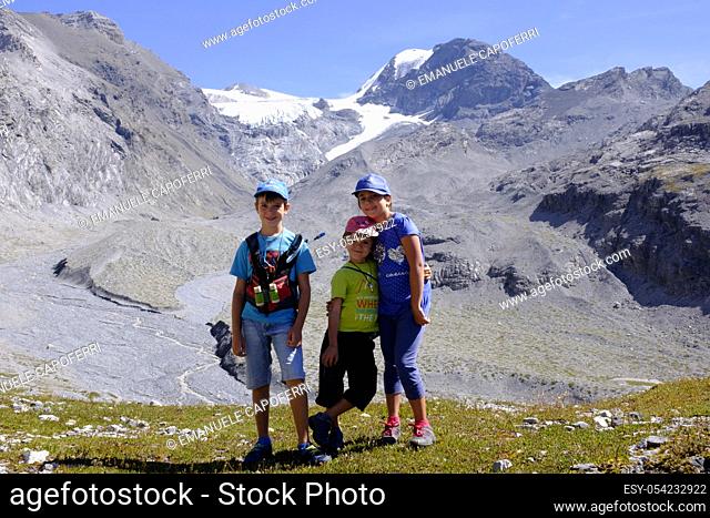 Portrait of three young brothers in the background the Crystal Mountain with glacier, Valley of Calves, Stelvio National Park, Ital