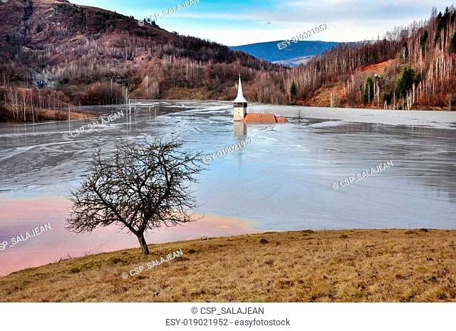 A flooded church in a toxic red lake. Water polluting by a copper mine. Rosia Montana, Romania