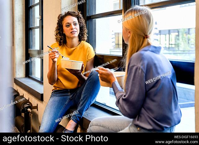 Businesswomen having lunch break at window sill