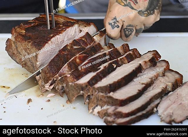 Themed photo grilling. Grilled pork, roast pork is portioned with a meat knife, cut into slices. Grilling on charcoal grill, grilled meat, charcoal