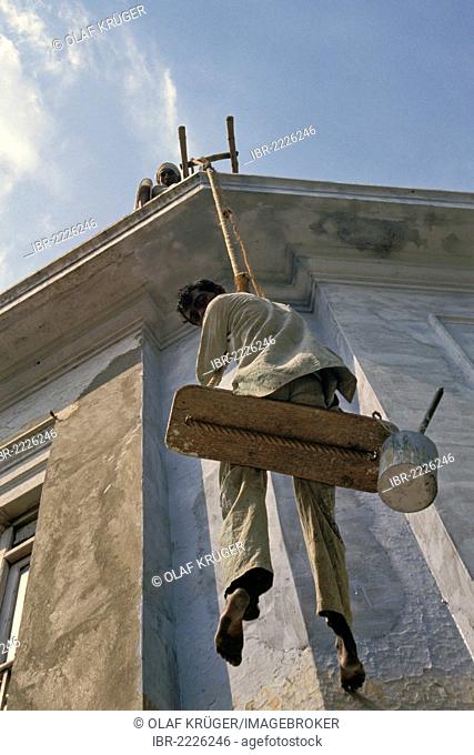 Facade painter sitting on an unstable construction, Connaught Place, Delhi, India, Asia