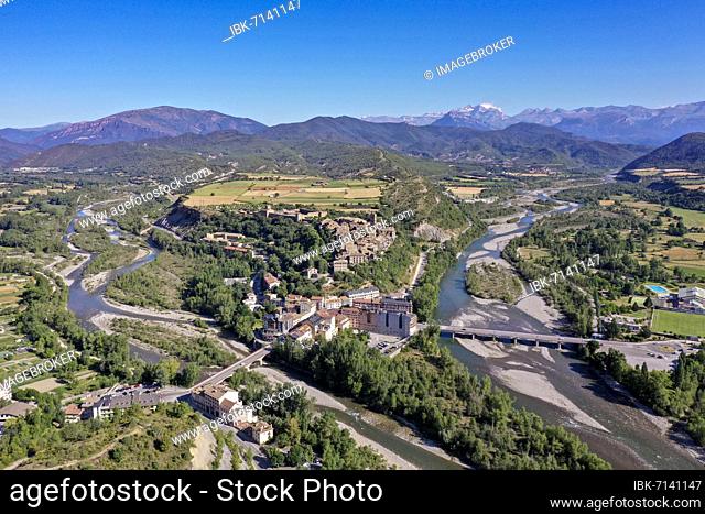 Drone shot, aerial view of the new town of Ainsa and the rivers Rio Cinca and Ara, behind it the historic old town of Ainsa and the mountains of the Pyrenees
