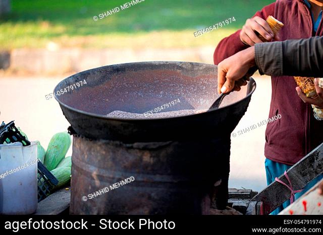 Islamabad, Islamabad Capital Territory, Pakistan - February 2, 2020, A Young boy is roasting fresh corn for the customers