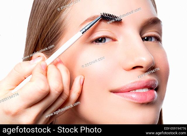 Beautician correcting eyebrows form on beautiful woman face. Beauty shot. Close-up