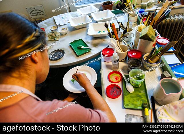 27 September 2023, Baden-Württemberg, Zell am Harmersbach: Ceramic painter Valentina Iffländer paints a plate with the traditional motif of rooster & hen
