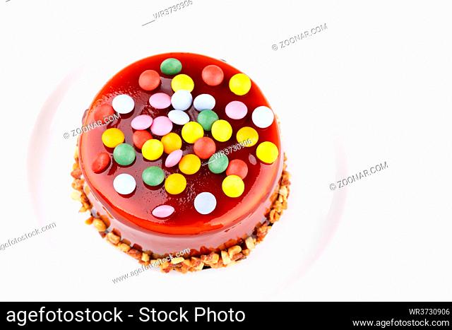 Caramel layered sponge cake with colorful sweet candies and nuts