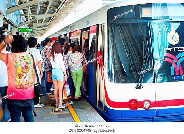 BANGKOK - MARCH 17, 2013: People board a BTS Skytrain at a city centre station. The Thai capital's BTS rail public transport system serves 600
