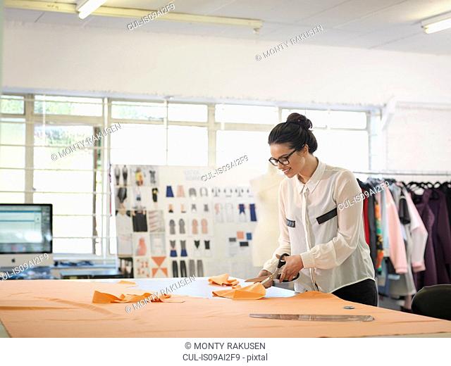 Fashion designer cutting cloth in fashion design studio