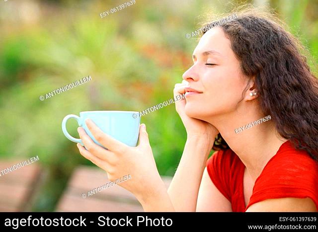 Profile of a relaxed woman resting holding a coffee cup in a park