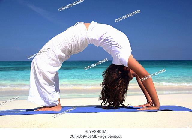 Young woman practicing yoga on beach, Paradise Island, Nassau, Bahamas