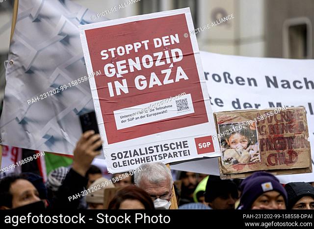 02 December 2023, North Rhine-Westphalia, Duesseldorf: Demonstrators hold up a sign reading ""Stop the genocide in Gaza"" at a pro-Palestine rally under the...