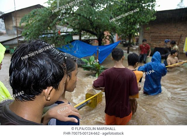 Flood victims, queuing to walk through fast-moving flood waters using rope, Pejaten, Jakarta, Java, Indonesia