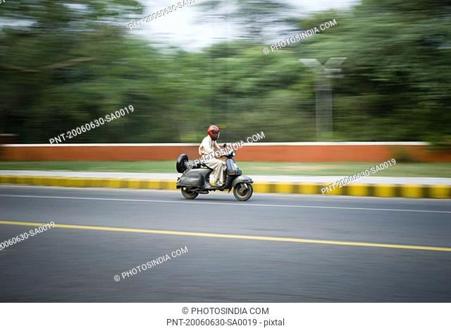 Side profile of a man riding a scooter, New Delhi, India