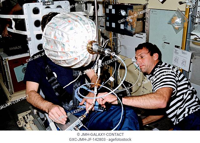 Astronaut David C. Hilmers (right), STS-42 mission specialist, assists European Space Agency (ESA) payload specialist Ulf Merbold with the visual stimulator...