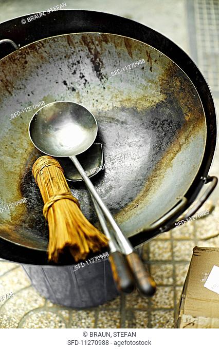 A bamboo whisk, a ladle and a spatula in a wok at a market in Saigon (Vietnam)