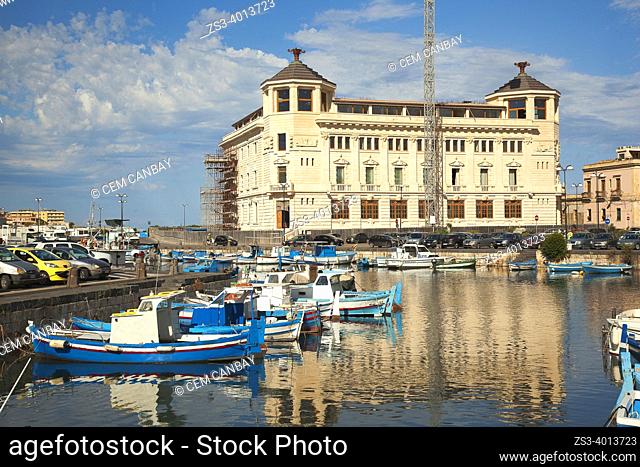 Traditional fishing boats inside the harbor of the Island Of Ortigia with the Post Office Building at the background, Ortigia island, Syracuse, Sicily, Italy