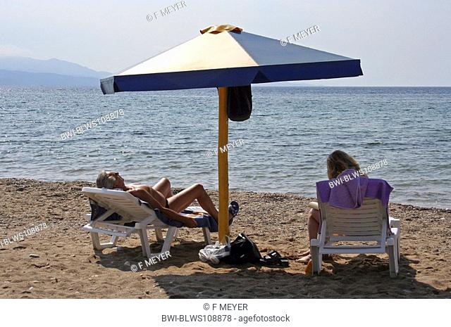 pensioner under a sunshade at the beach, Greece, Aegean Sea