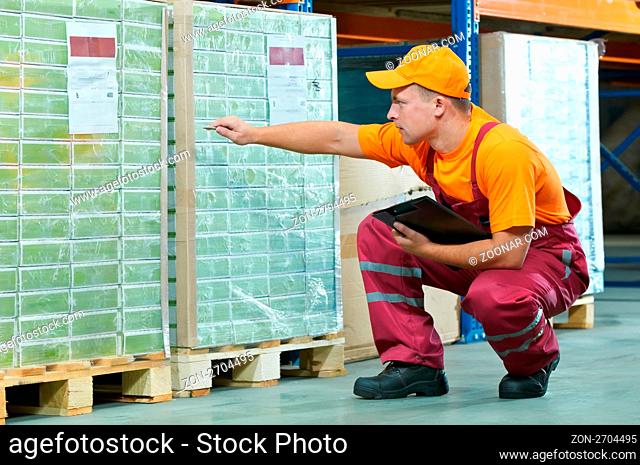 young worker man in uniform at warehouse checking rack arrangement of laminate flooring
