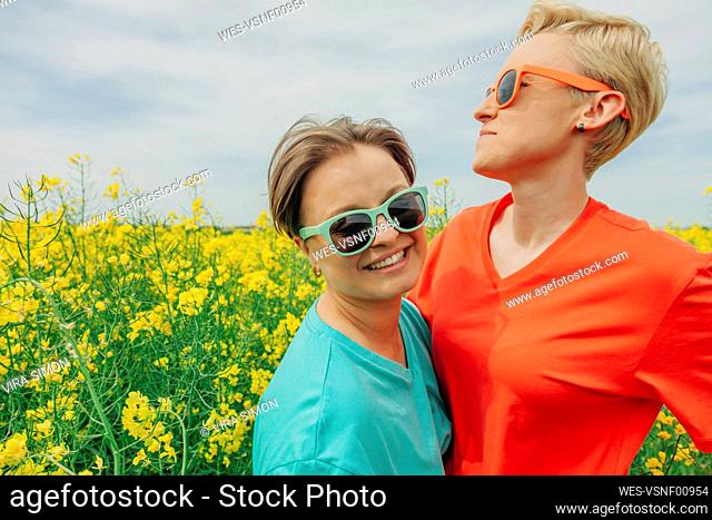 Happy lesbian couple wearing sunglasses at field