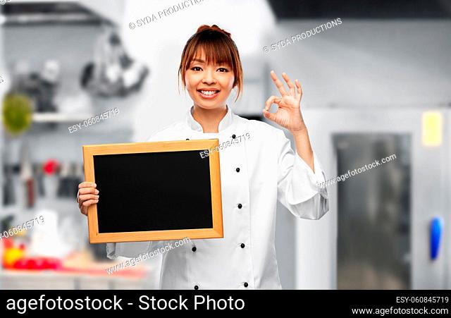 female chef with chalkboard showing ok on kitchen